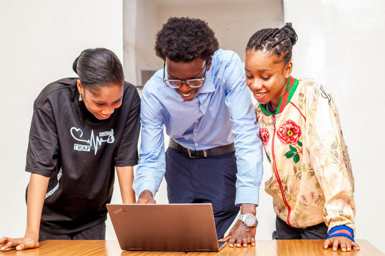 About Three young adults collaborating on a laptop for a digital project indoors.